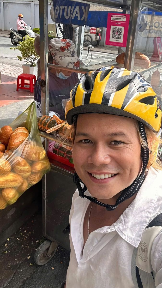 Tình Ca đội mũ bảo hiểm, mỉm cười bên xe trái cây ven đường